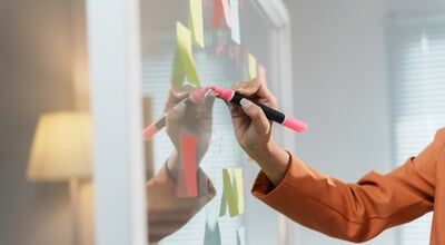 Businesswoman,Is,Writing,On,A,Transparent,Whiteboard,With,A,Pink