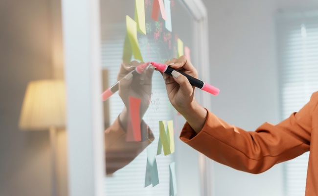 Businesswoman,Is,Writing,On,A,Transparent,Whiteboard,With,A,Pink