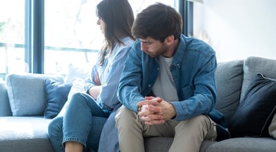 Millennial,Couple,Sitting,On,The,Couch,At,Home,,Facing,Away