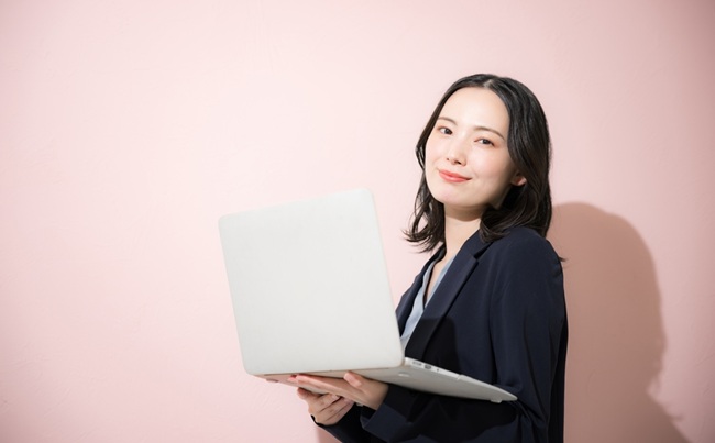 A,Young,,Cute,Woman,In,A,Suit,Holding,A,Computer,