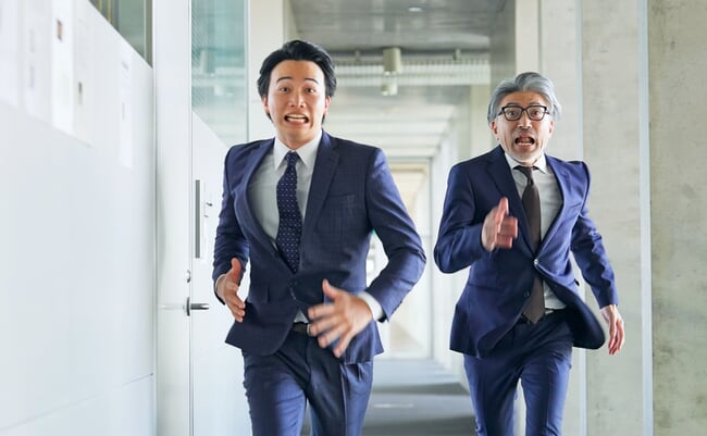 Two,Business,People,Running,Through,The,Corridor,Of,A,Building