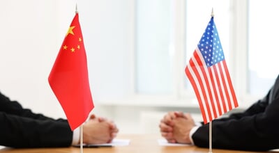 Diplomats,Negotiating,During,Meeting,At,Table,Indoors,,Focus,On,Flags