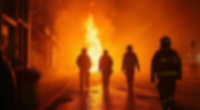 A,Blurred,View,Of,Four,Firefighters,Walking,Toward,A,Towering