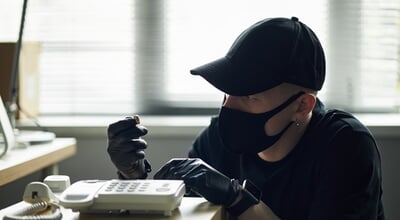 Man,Wearing,Black,Cap,And,Mask,Tampering,With,Landline,Phone