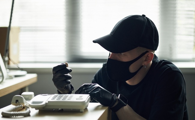 Man,Wearing,Black,Cap,And,Mask,Tampering,With,Landline,Phone