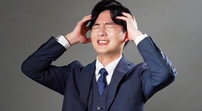 Asian,Businessman,Holding,His,Head,In,Black,Background