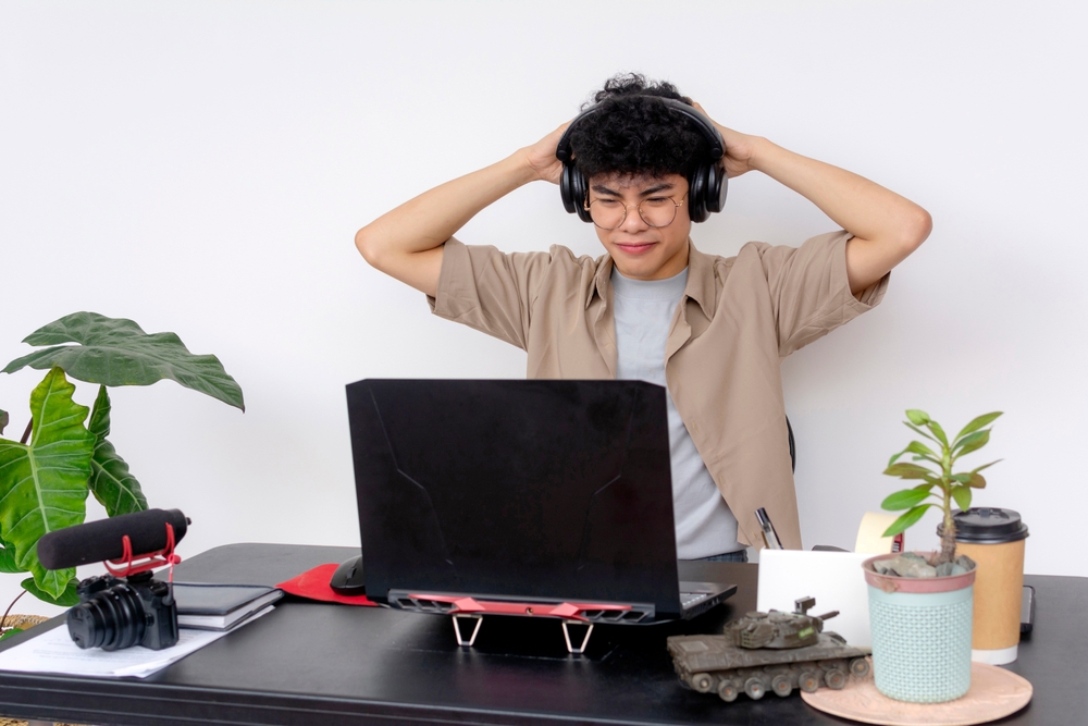 A,Young,Asian,Freelance,Video,Editor,Working,With,Headphones,On