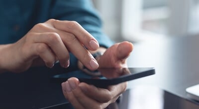 Woman,Using,Mobile,Phone,With,Laptop,Computer,On,Office,Table.