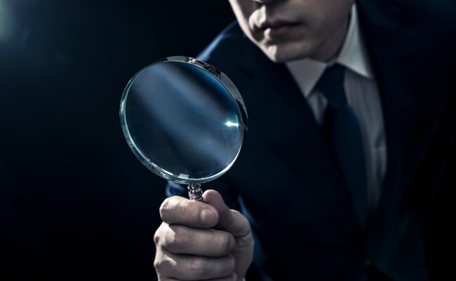 Male,Businessman,Peering,Through,Magnifying,Glass