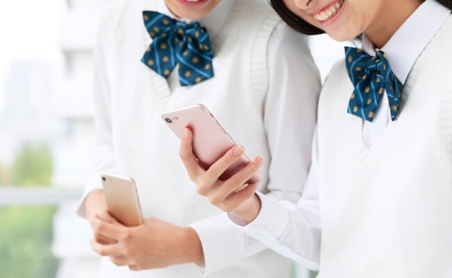 Female,Student,In,Uniform,With,Smartphone