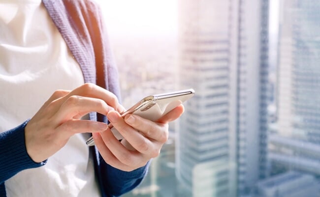 A,Woman,Operating,A,Smartphone,With,The,City,In,The