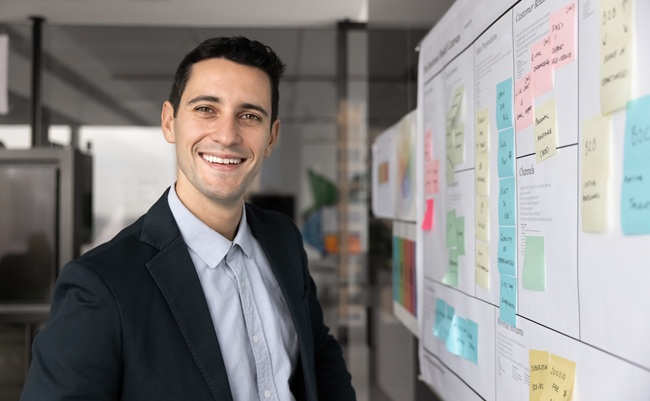 Happy,Handsome,Young,Executive,Man,Standing,At,Kanban,Board,,Looking