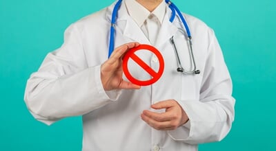 Male,Doctor,Holding,Prohibited,Sign,Over,Blue,Background