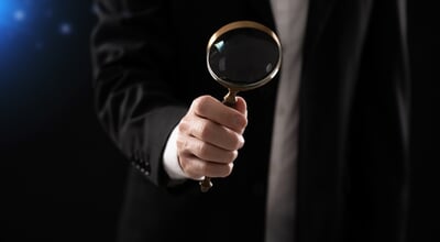 Close-up,Of,A,Businessman,Holding,A,Magnifying,Glass,In,A