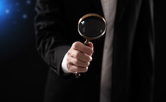 Close-up,Of,A,Businessman,Holding,A,Magnifying,Glass,In,A
