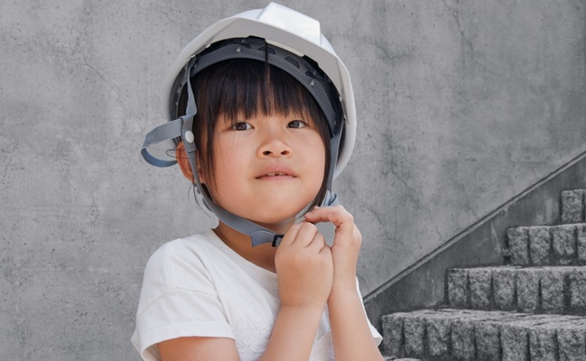 An,Elementary,School,Girl,Wearing,A,Helmet,Against,A,Concrete