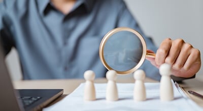 Close-up,Of,A,Person,Using,Magnifying,Glass,To,Examine,Wooden