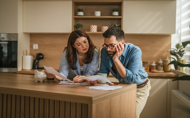 Young,Couple,In,Their,Kitchen,Reviewing,Important,Bills,And,Documents,