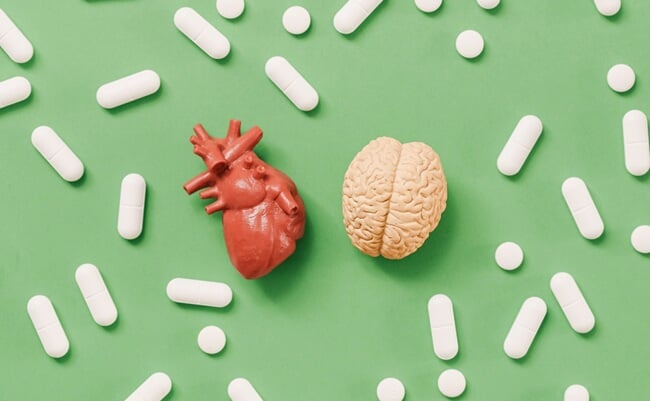 Heart,Versus,Brain,Concept,With,Medical,Pills,On,Green,Background.