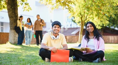 Young,Indian,Students,Are,Sitting,On,The,Green,Grass,Of