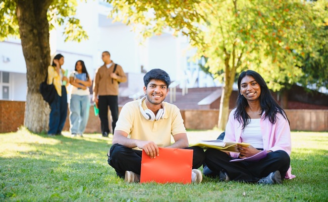 Young,Indian,Students,Are,Sitting,On,The,Green,Grass,Of