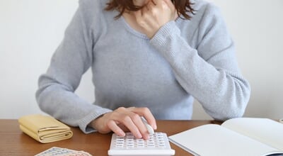 Japanese,Woman,Calculating,Household,Budget,With,Calculator,,Cash,,And,Notebook,