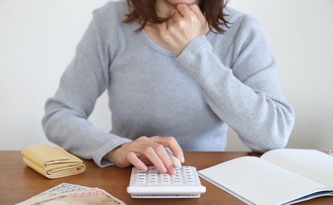 Japanese,Woman,Calculating,Household,Budget,With,Calculator,,Cash,,And,Notebook,